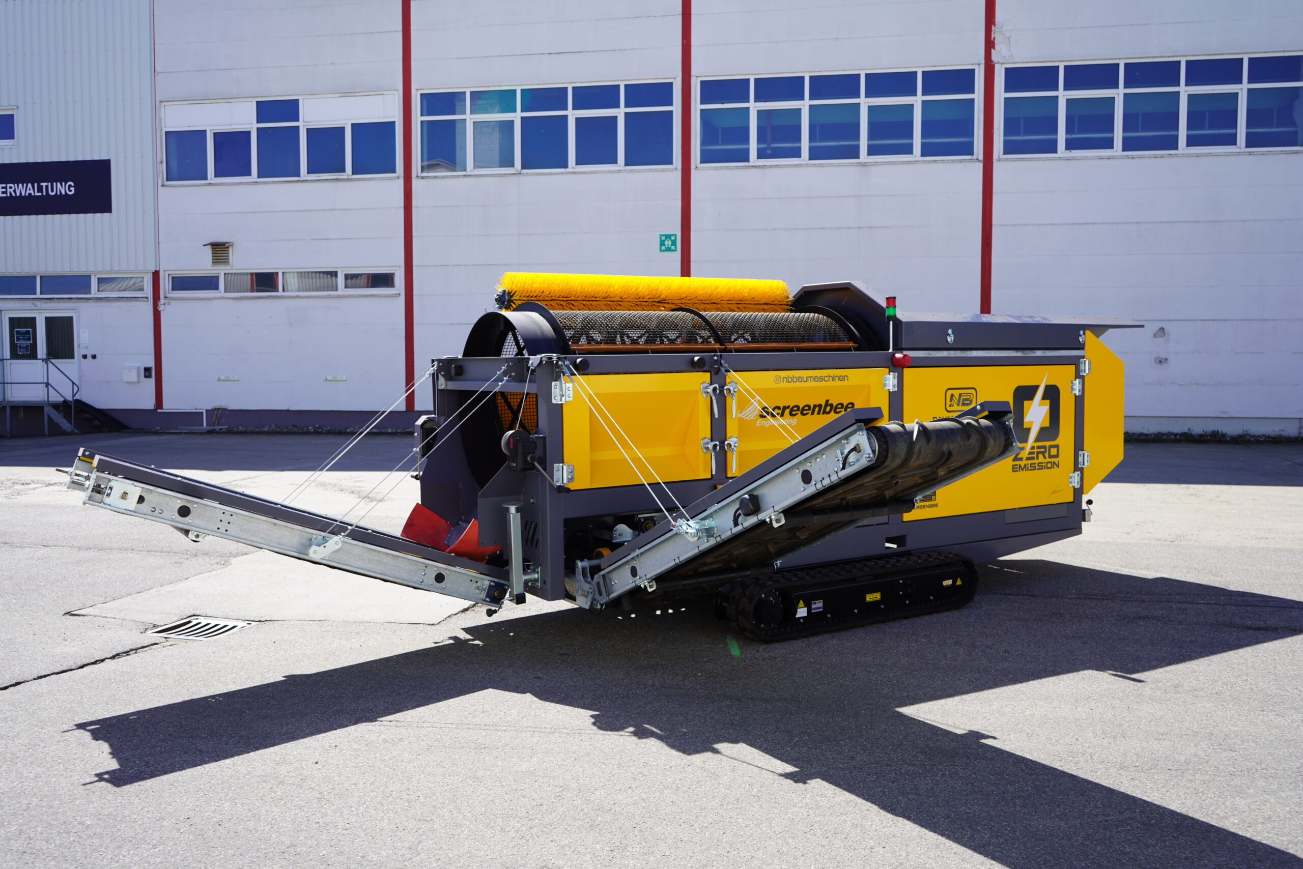 Gelb-schwarze Screenbee-Siebanlage mit Förderbändern und Bürstenmodul steht vor einer hellen Industriehalle; auf der Seite steht Zero Emission.