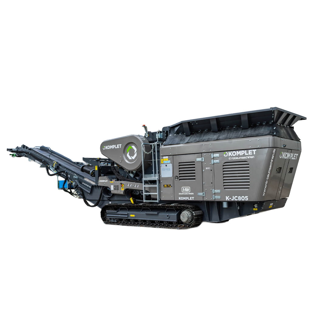 Großer grauer KOMPLET K-JC805 Backenbrecher steht auf Raupenfahrwerk im Freien; seitliche Förderbänder, Trichter und Gehäuse mit NB-Baumaschinen-Logo sind sichtbar.