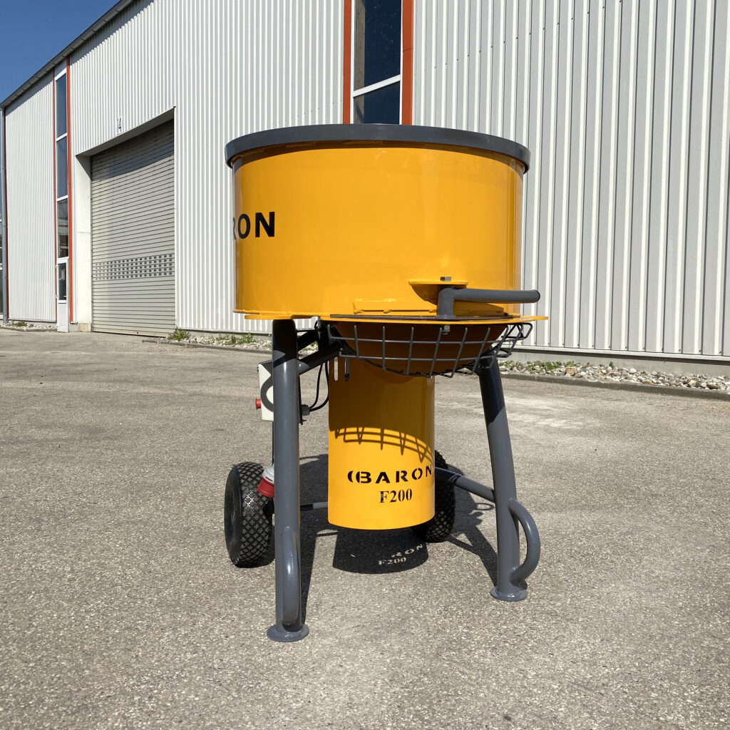 Der gelbe Baron F200 Zwangsmischer steht vor einer hellen Industriehalle, mit grauem Rahmen, breiten Rädern und klar sichtbarer Beschriftung im Freien.