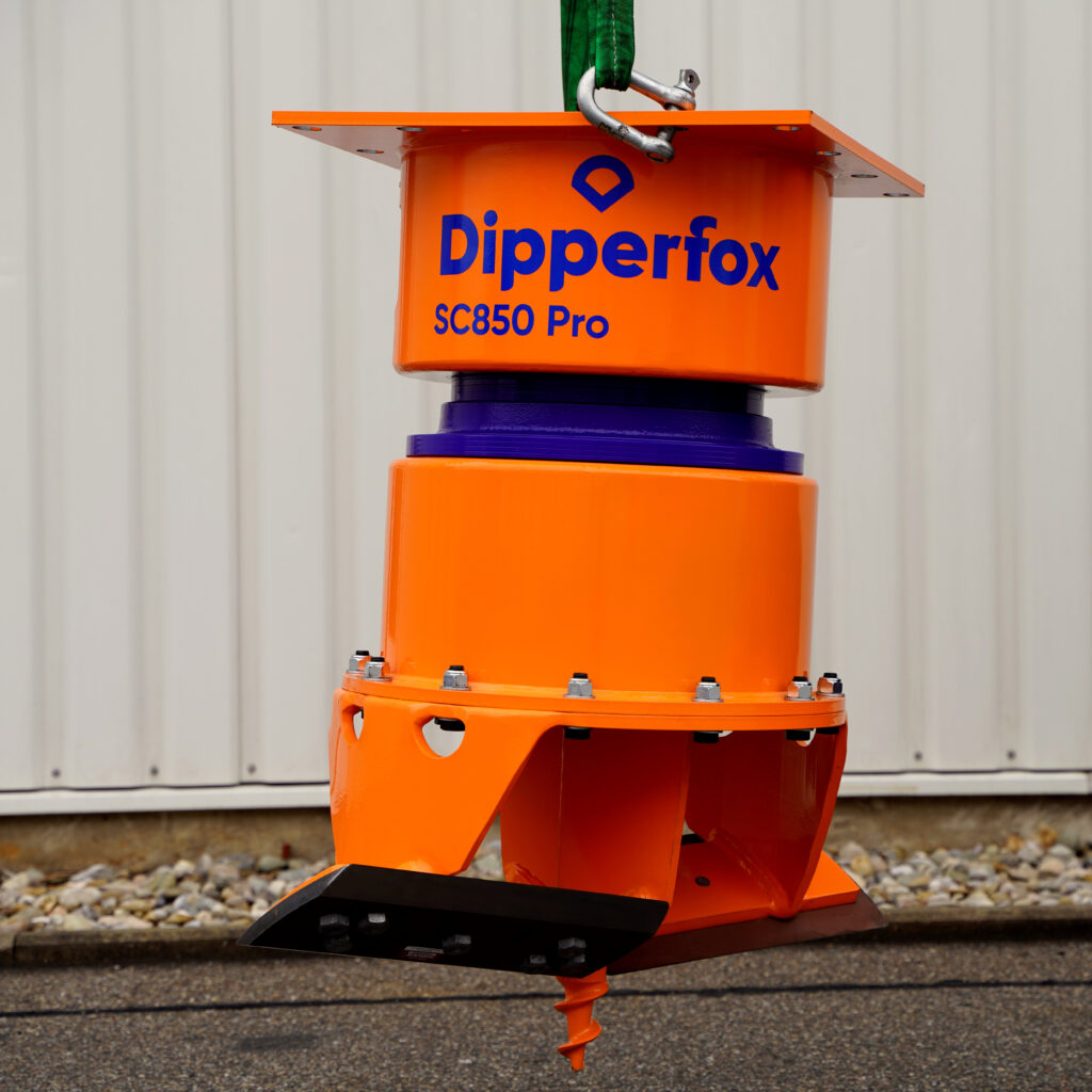 Ein orangefarbener Pipperfox SC850 Pro hängt an einem grünen Hebeband, mit violettem Zwischenring und spiralförmigem Bohrer vor heller Wand.