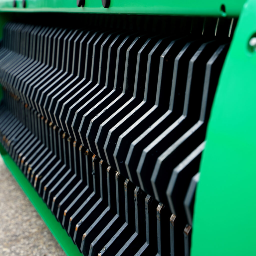 Die grüne Metallverkleidung zeigt ein enges, schwarz-silbernes Gitter mit schrägen Lamellen und leichten Gebrauchsspuren.