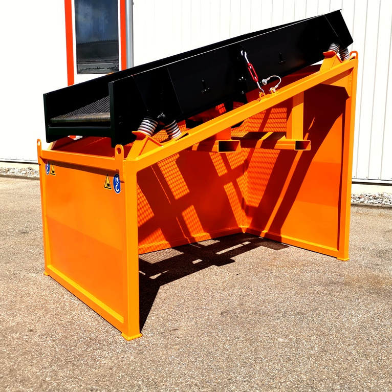 Orange und schwarze Siebanlage mit schrägem Förderband und Stahlrahmen vor einer hellen Industriehalle im Sonnenlicht.