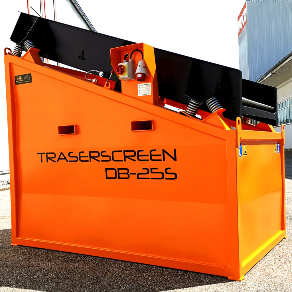 Eine orange-schwarze TRASERSCREEN DB-25S-Siebanlage steht vor einem Industriegebäude, mit schrägem Förderteil, Federn und sichtbaren Anschlüssen.