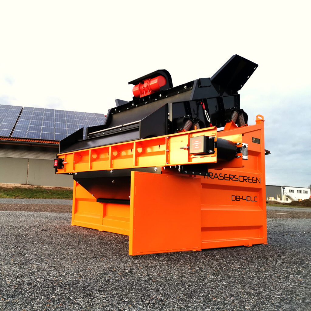 Große orange-schwarze Siebmaschine DB-40LC mit robustem Aufbau, Fördertechnik und Trichter steht auf einem Kiesplatz vor Solarmodulen.
