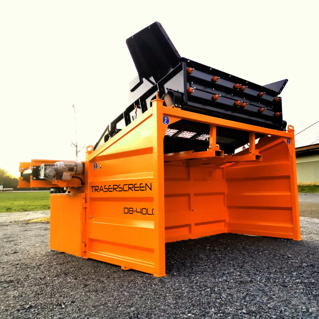 Große orange-schwarze Trennanlage von TRASERSCREEN mit Aufgabetrichter, mehreren Siebwalzen und robustem Stahlgehäuse auf Schotter.