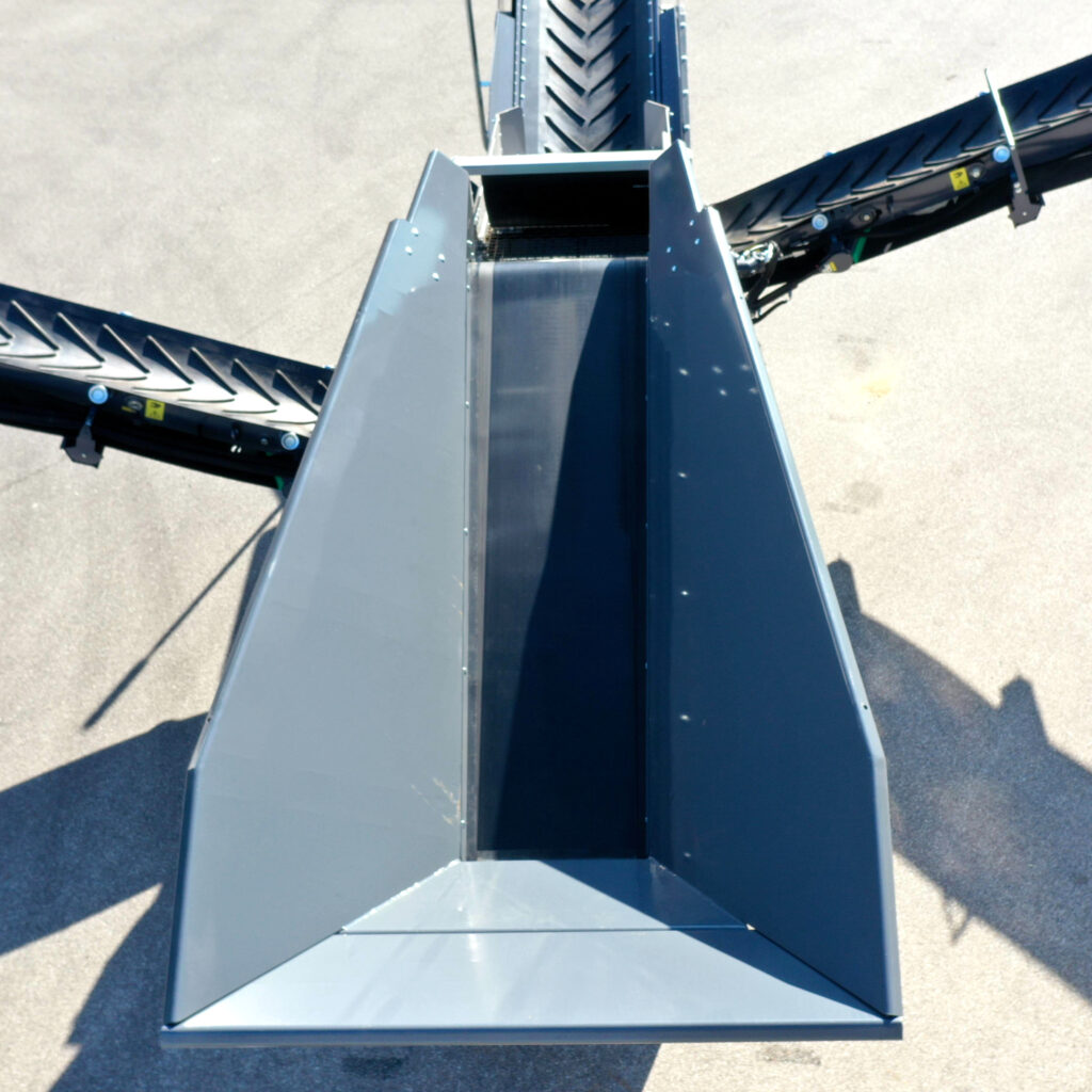 Dunkelblaue Förderbänder und ein zentraler Trichter der Recyclinganlage stehen auf hellem Boden, mit sichtbaren Schutzleisten, Rollen und Metallkanten.
