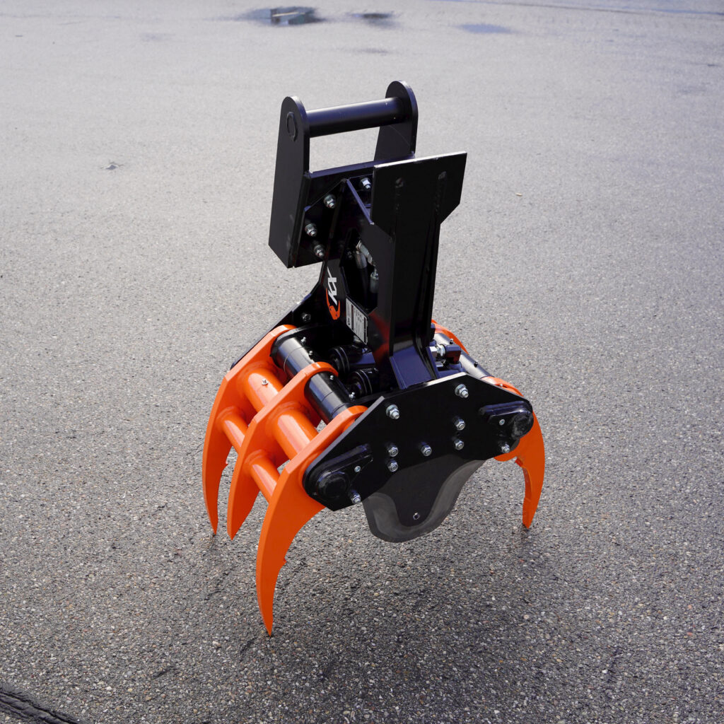 Ein orange-schwarzer Fällgreifer KX-210-5 steht auf Asphalt, mit mehreren Greifarmen, massiven Bolzen und einem robusten schwarzen Oberteil.