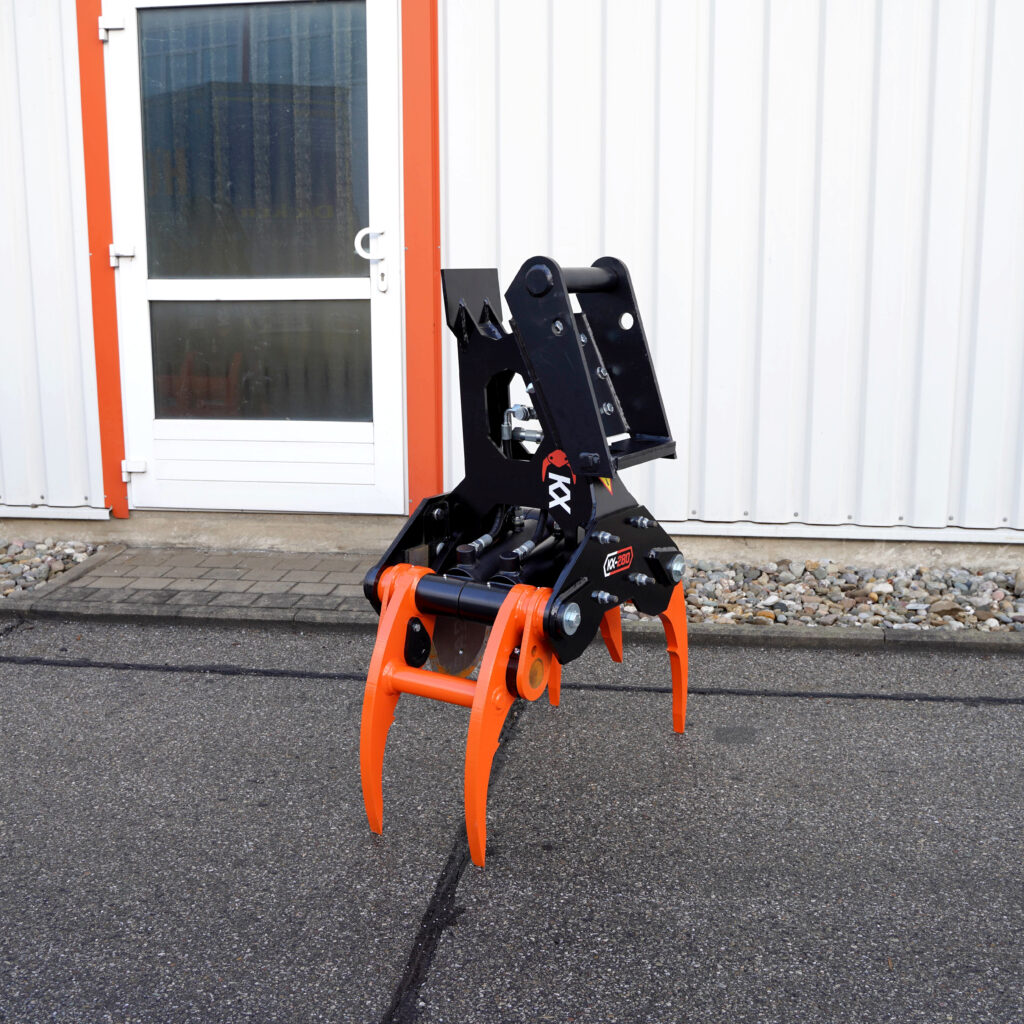 Ein schwarz-orangefarbener Fällgreifer KX-280-3 mit Hydraulikanschlüssen steht vor einer weißen Metallfassade mit Tür und roten Rahmenleisten.