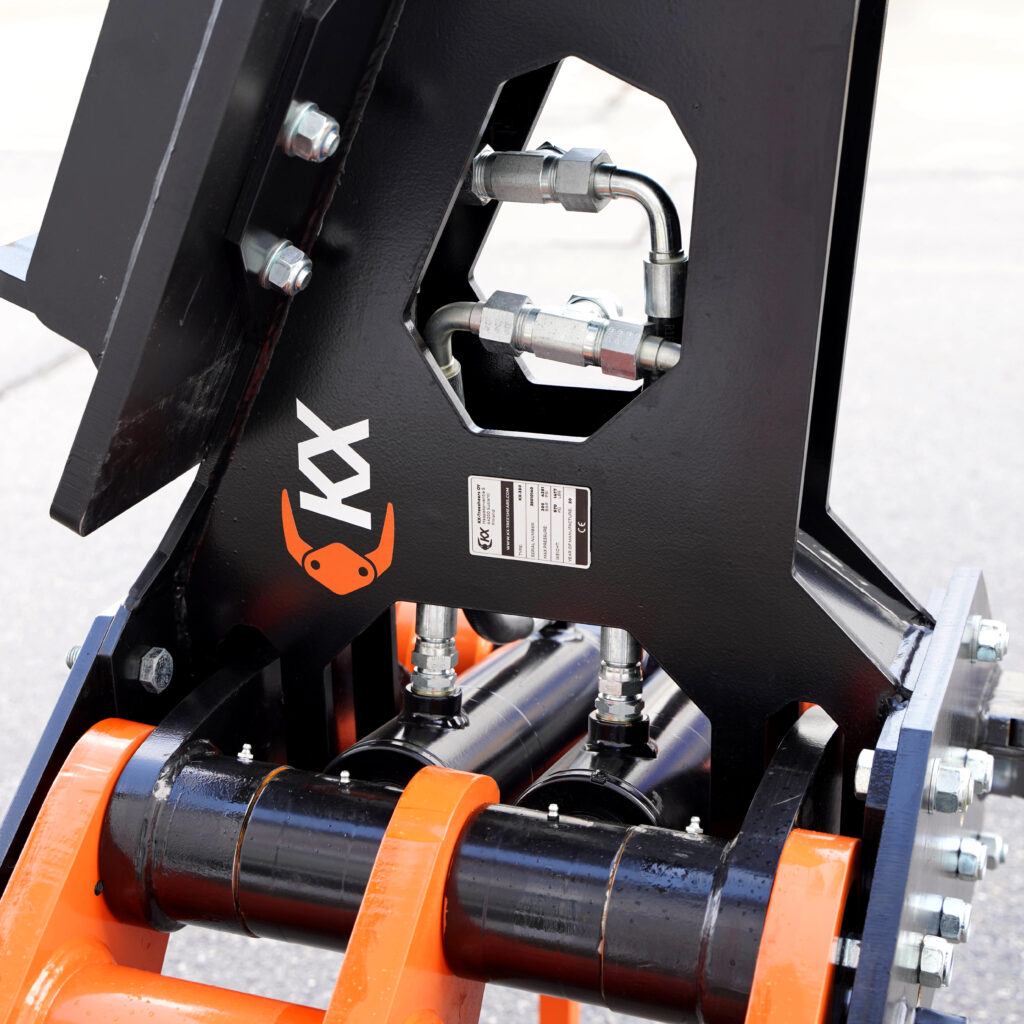 Schwarzer Fällgreifer KX-350 mit orangefarbenen Elementen, sichtbaren Hydraulikleitungen und massiven Bolzen vor hellem Hintergrund.