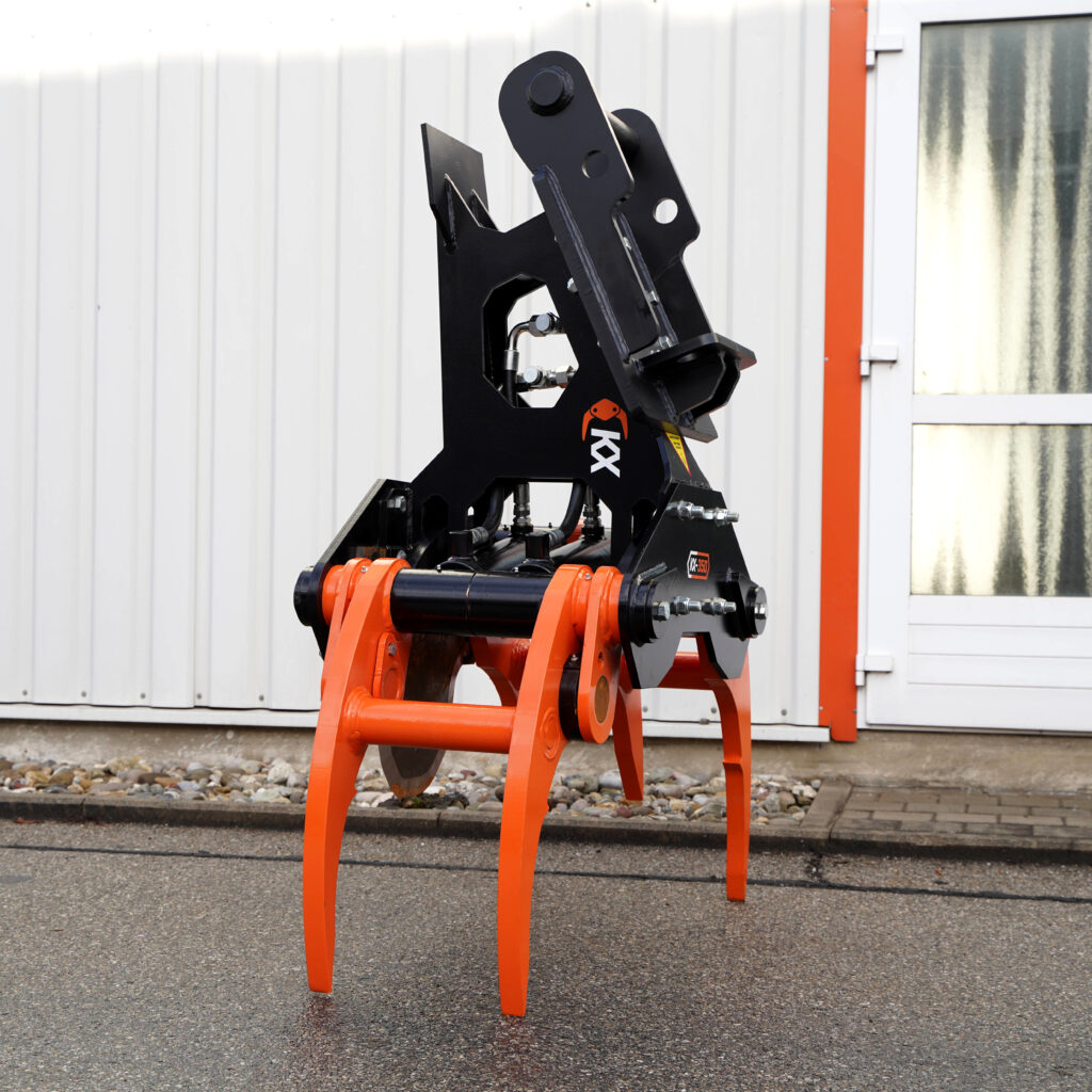 Ein schwarzer und orangefarbener KX-350-3 Fällgreifer steht vor einer hellen Hallenwand mit Hydraulikzylinder, Greifarmen und Metallrahmen.