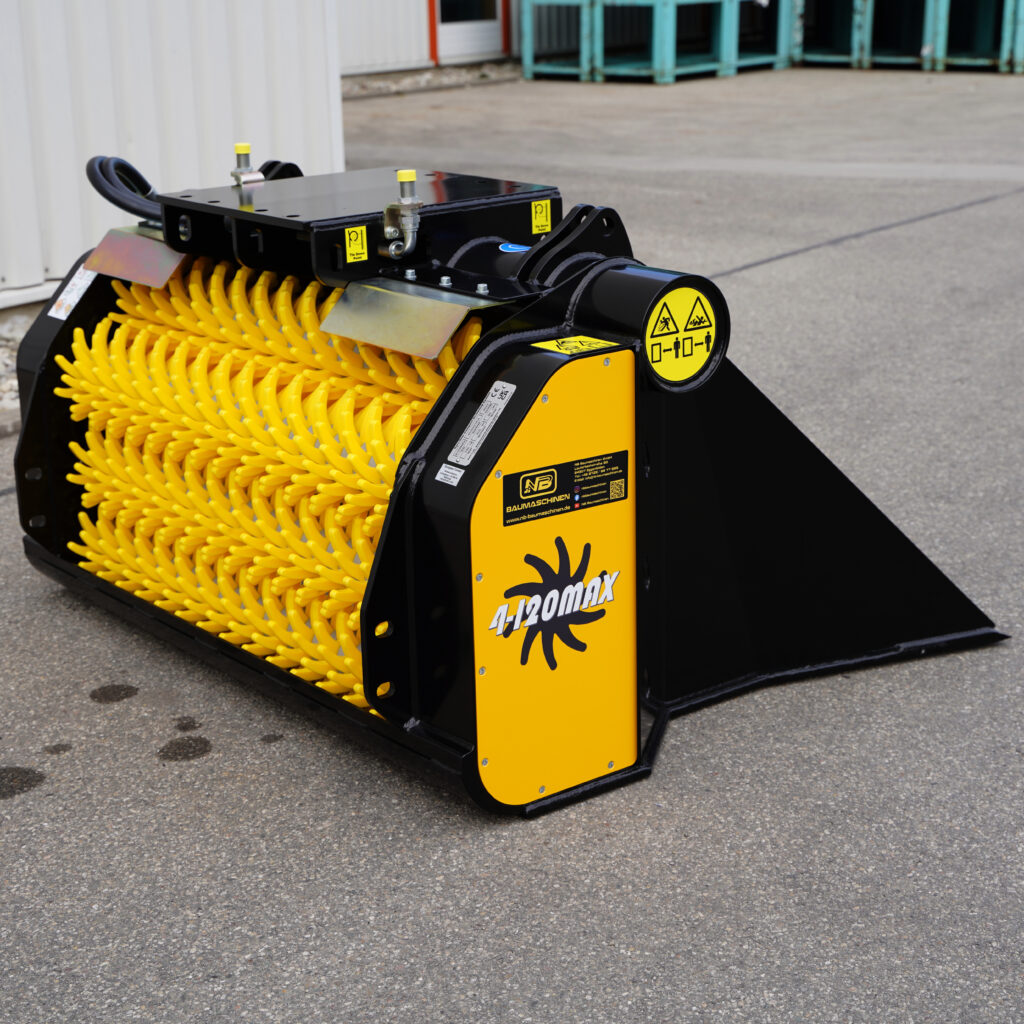 Ein schwarz-gelber GYRUstar 4-120MAX-3 mit gelben Borstenwalzen, Warnsymbolen und Frontschaufel steht auf grauem Asphalt vor einer Halle.