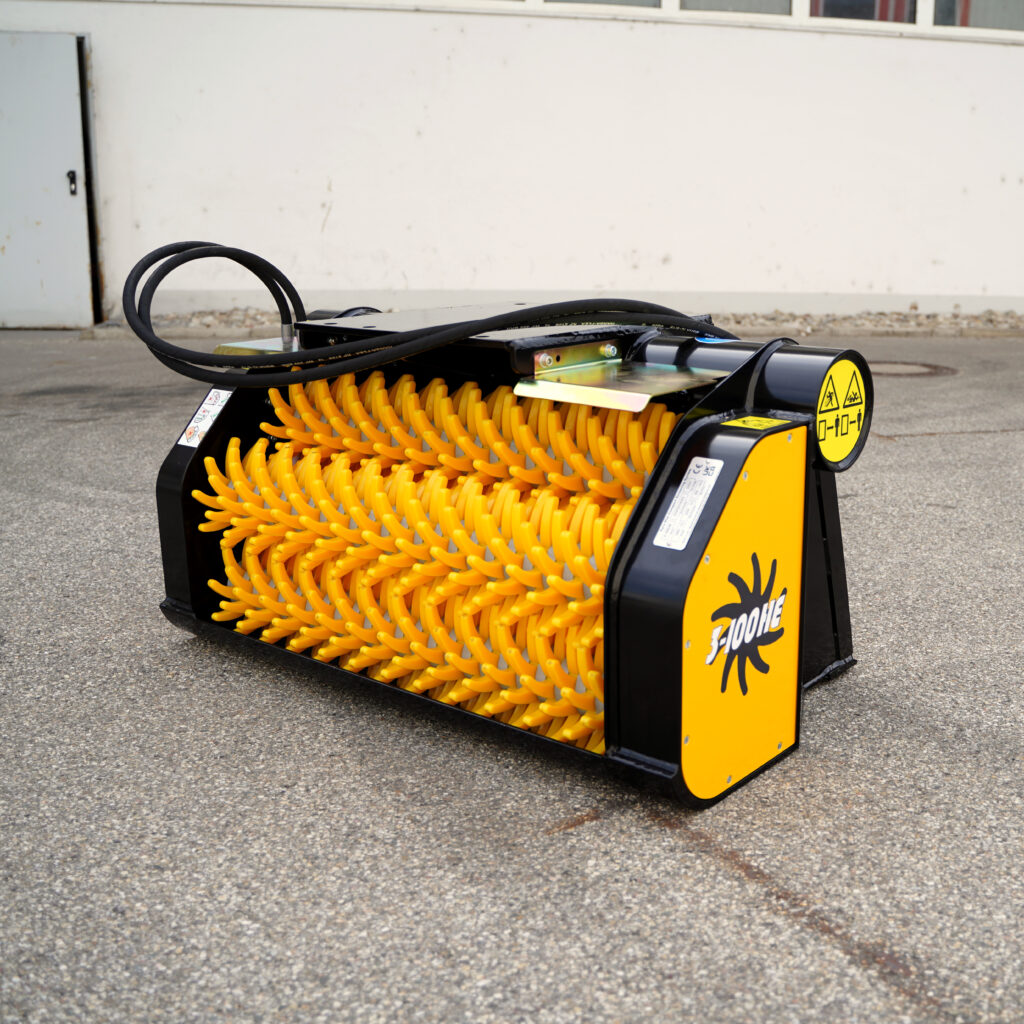 Kompakter GYRUstar 3-100HE-3 mit gelbem Schneidwerk und schwarzen Anschlüssen steht auf Asphalt vor einer hellen Wand.