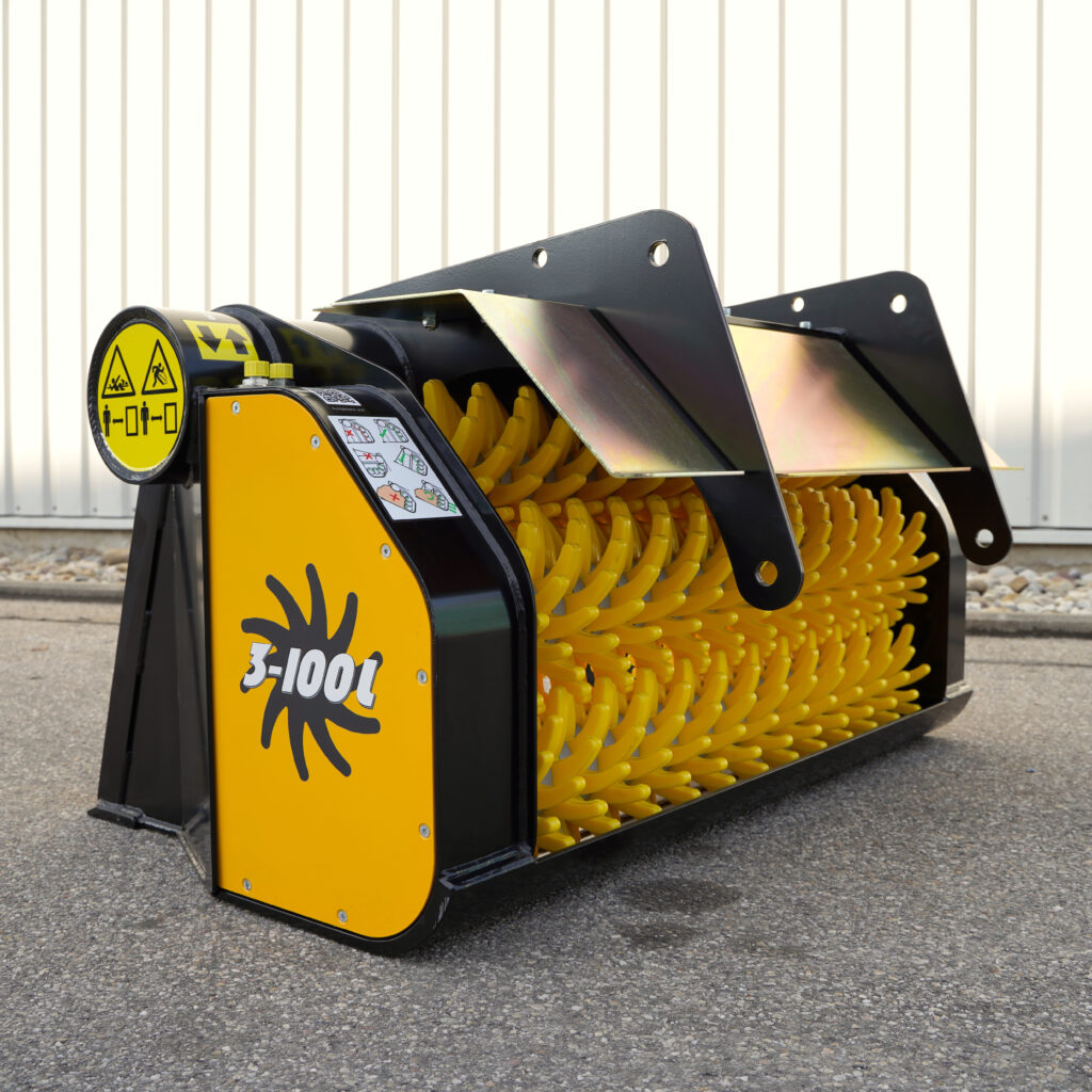 Ein gelb-schwarzer GYRUstar 3-100L mit vielen gelben, gebogenen Sternwalzen steht auf Asphalt vor einer hellen Metallwand und einem stabilen Rahmen.