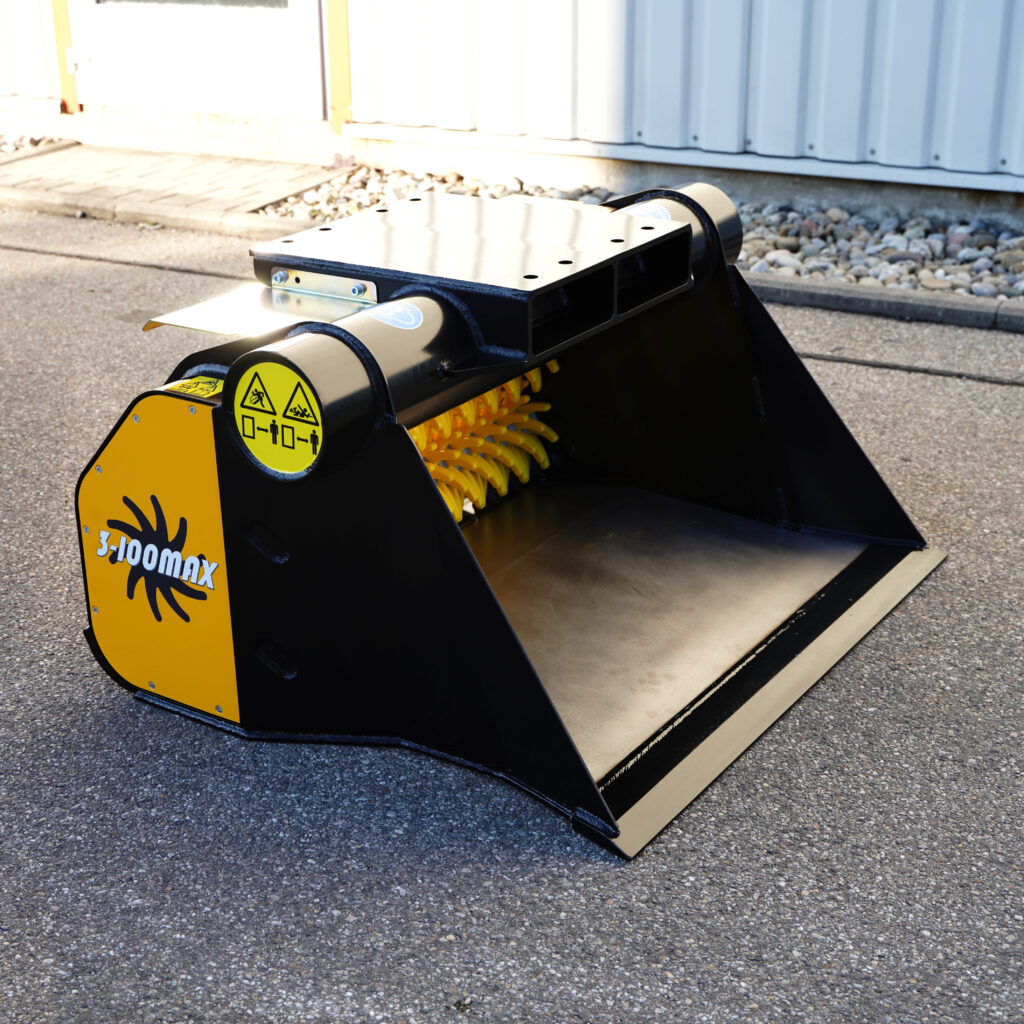 Der schwarze und gelbe GYRUstar 3-100MAX Greifer steht auf Asphalt, mit breiter Schaufel, Warnsymbolen und gelbem Schneidwerk innen.