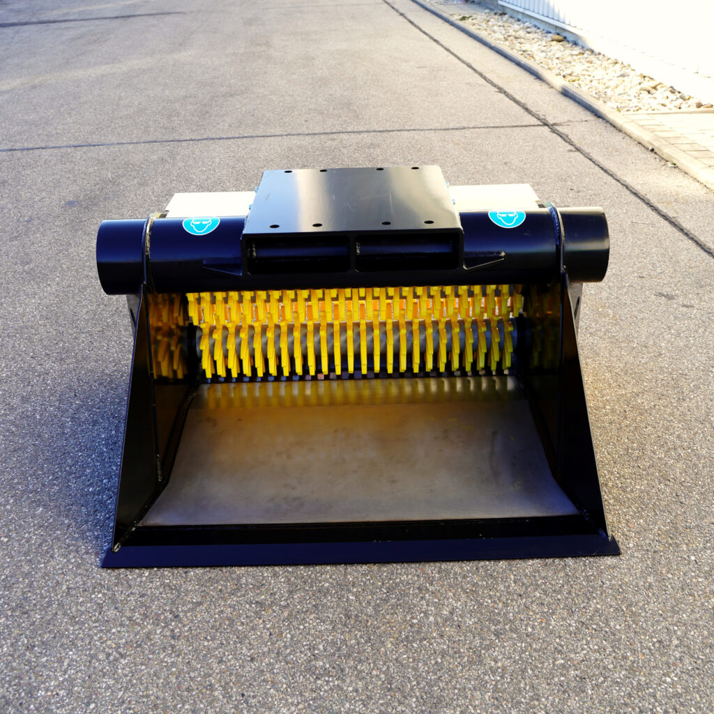Vor einer Asphaltfläche steht ein schwarzer GYRUstar mit gelben Schneideelementen und breiter Öffnung, die Oberseite zeigt glatte Metallplatten.
