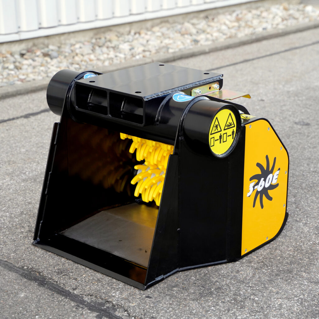 Der schwarze GYRUstar 3-60E-7 mit gelben Zerkleinerungswalzen und Warnaufklebern steht auf Asphalt vor einer hellen Wand im Freien.