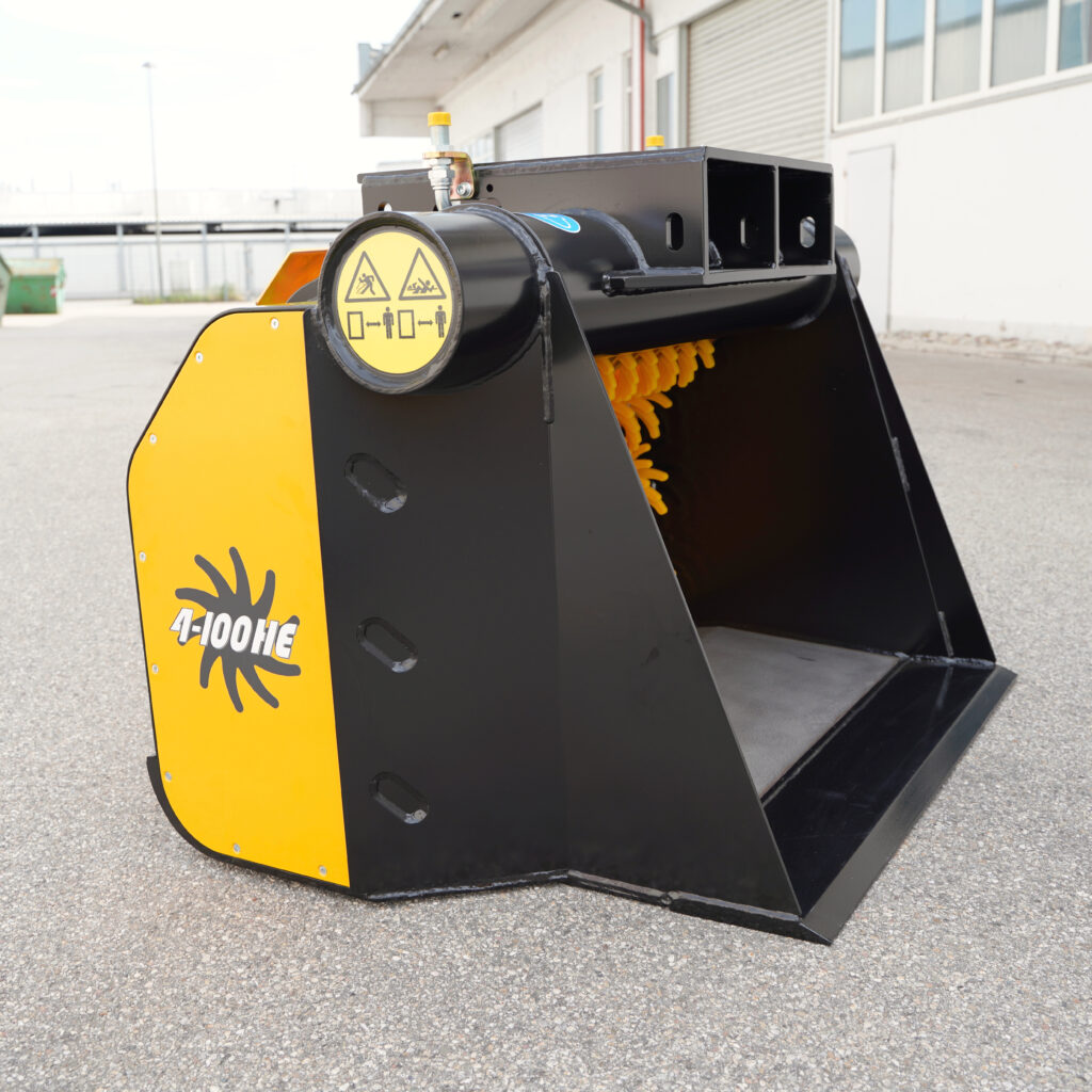 Ein schwarz-gelber GYRUstar 4-100HE mit Warnsymbolen und offener Schaufel steht vor einer Industriehalle auf Asphalt im Freien.