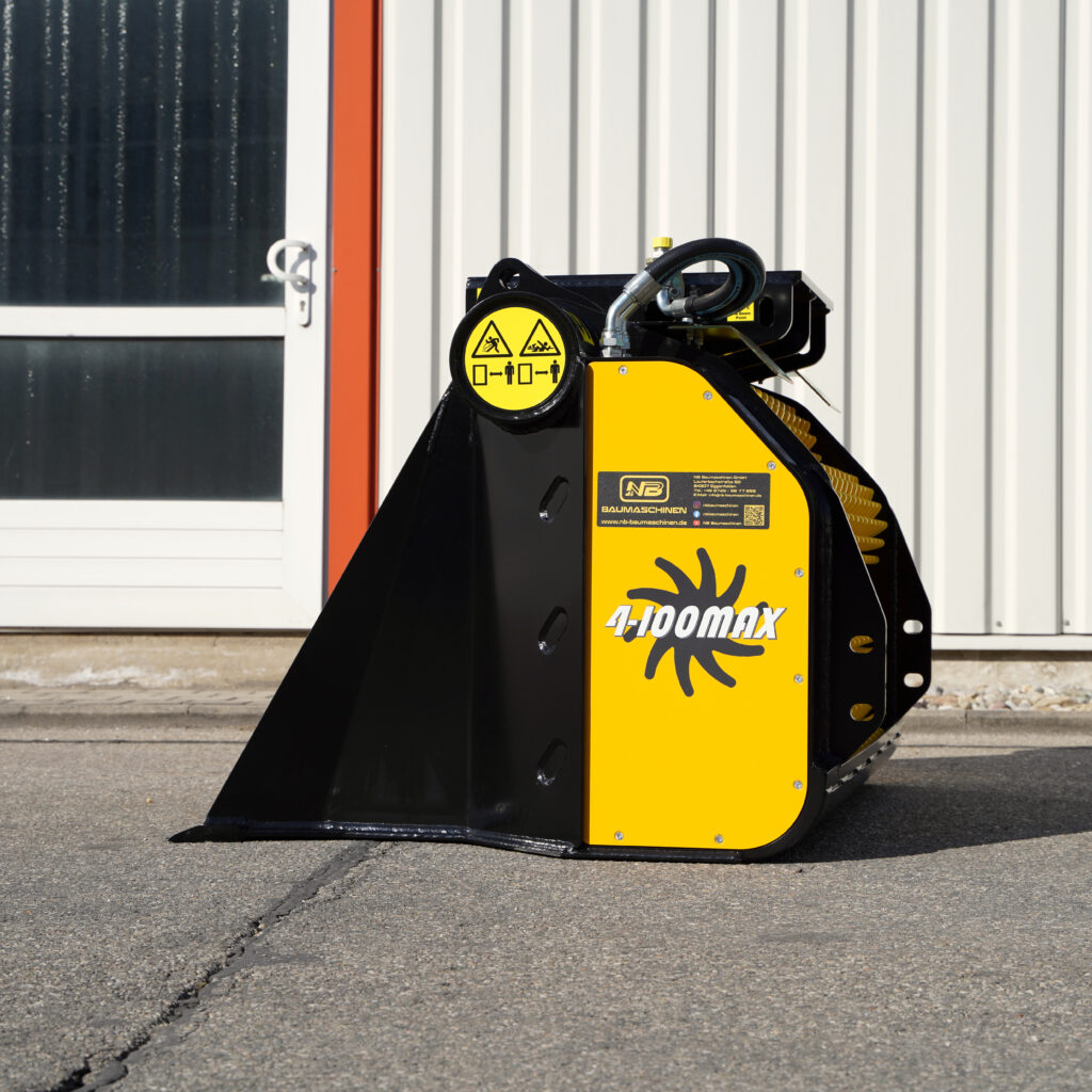 Schwarzer und gelber GYRUstar 4-100MAX-3 mit Hydraulikschlauch und Warnsymbolen steht vor einer hellen Metallfassade auf Asphalt.