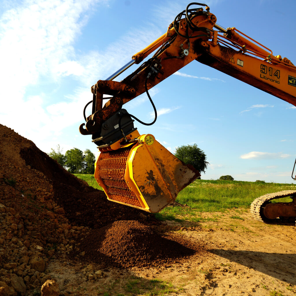 Ein gelber GYRUstar 6-150HDX-2 trennt auf einer Baustelle Erdreich, während das Förderrad Material in den Bodenbereich abwirft.
