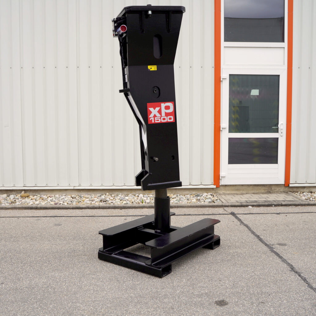 Ein schwarzer Hydraulikhammer XP1500-3 steht vor einer hellen Metallfassade, daneben eine Tür mit orangefarbenem Rahmen und Fenster.