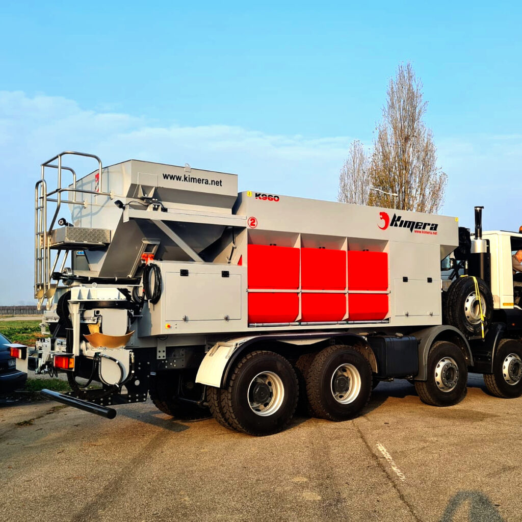 Große Kimera K960 Recyclingmaschine auf einem Lkw-Anhänger mit roten Seitenpanelen, grauem Aufbau und sichtbaren Wartungsplattformen im Freien.