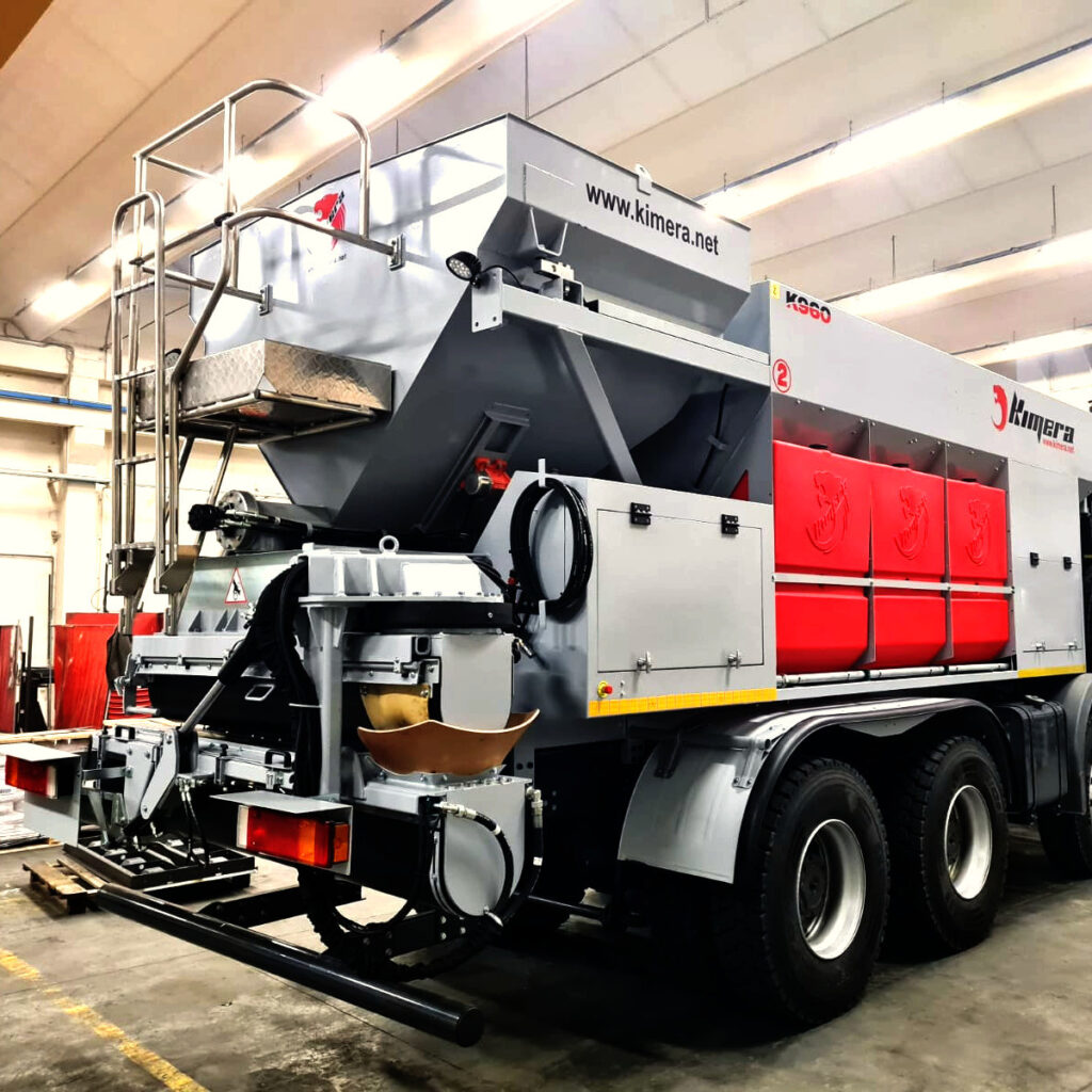 Ein grauroter Kimera K960 mit sichtbaren Hydraulik- und Wartungselementen steht in einer Werkhalle unter hellen Deckenleuchten.
