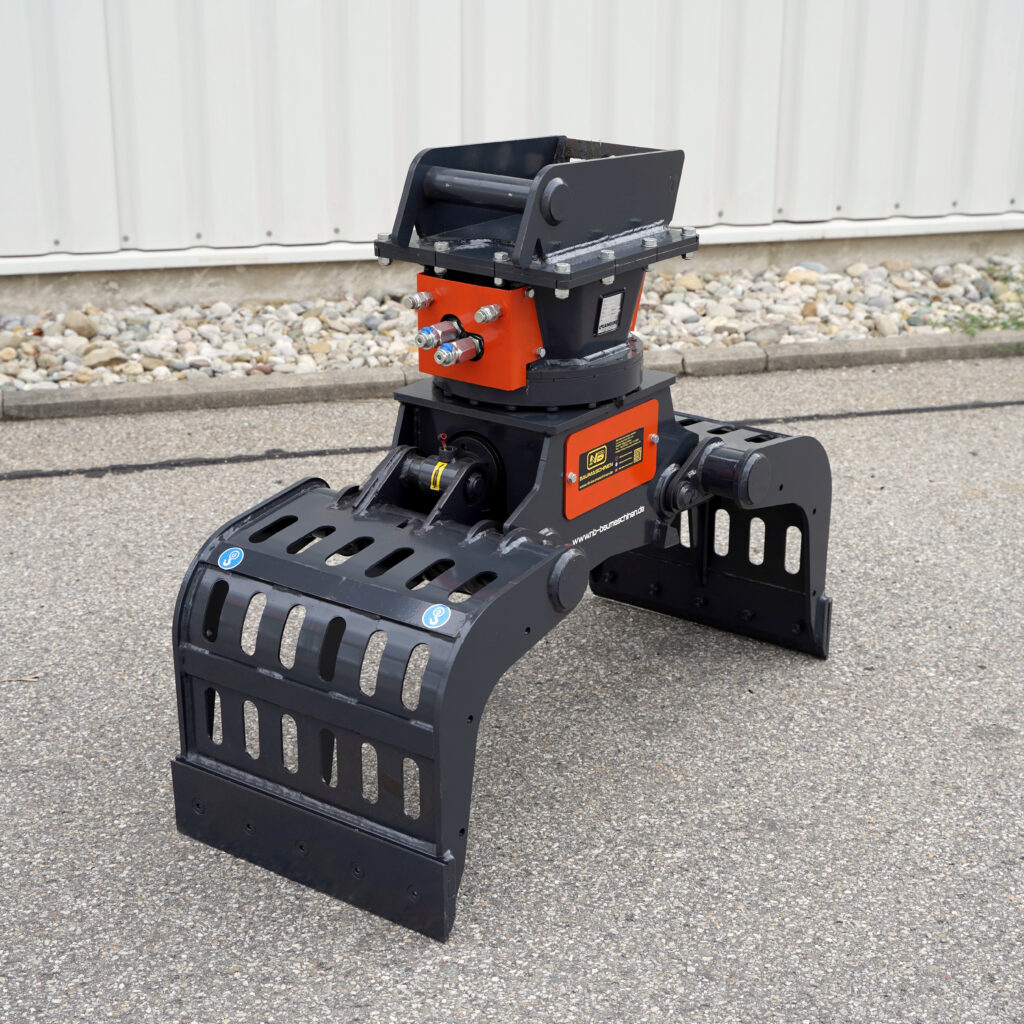 Schwarzer Sortiergreifer mit orangefarbenen Seitenteilen und robuster Drehaufnahme steht auf Asphalt vor einer hellen Metallfassade.