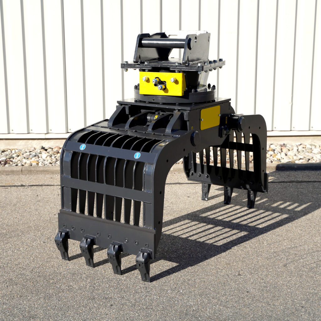 Ein schwarzer Sortiergreifer PG450-5 mit gelben Akzenten steht auf Asphalt vor einer weißen Metallwand und zeigt seine massiven Zinken.