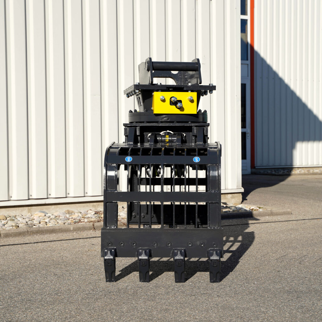 Schwarzer und gelber Sortiergreifer PG450-6 mit robustem Gitterrahmen steht vor einer hellen Metallfassade und wirft einen klaren Schatten.