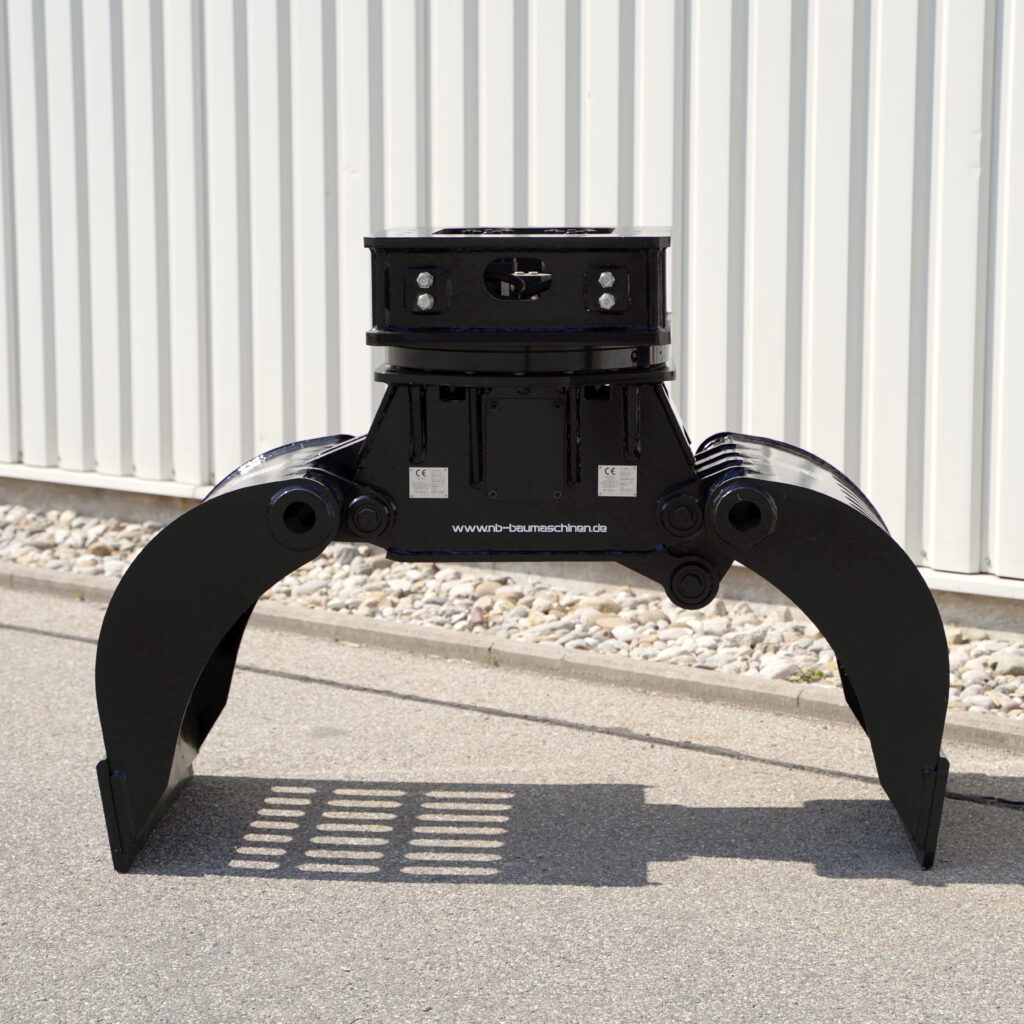 Ein schwarzer Sortiergreifer SG10.16-2 steht vor einer hellen Metallfassade, mit weit geöffneten Greifarmen und sichtbaren Bolzen auf dem Asphalt.