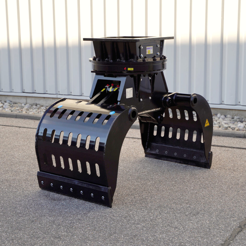 Ein schwarzer Sortiergreifer SG5.8-3 mit zwei breiten Greifarmen und gelochten Flächen steht auf Asphalt vor einer hellen Metallwand im Freien.
