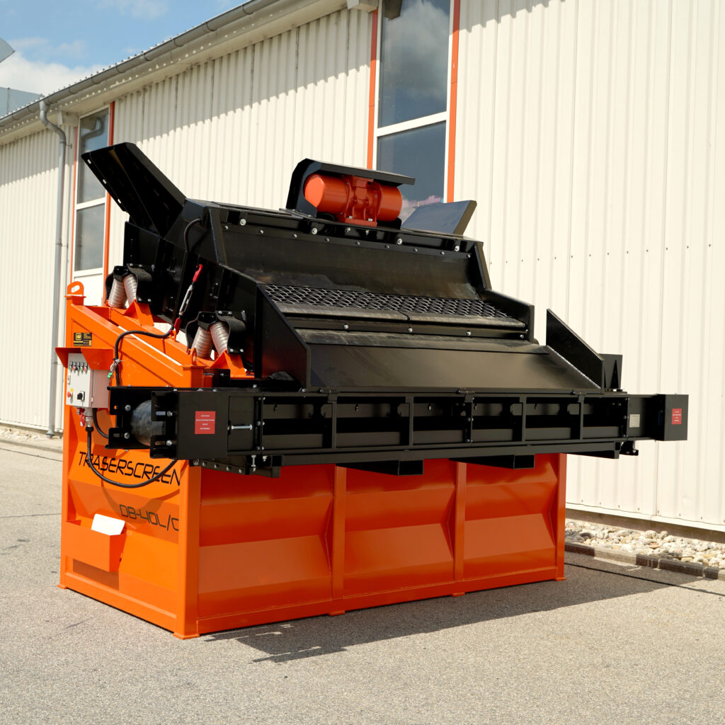 Orange-schwarze Traserscreen DB-40LC/2 steht im Tageslicht vor einer hellen Metallhalle; Förderbänder, Siebdeck und Antrieb sind klar sichtbar.
