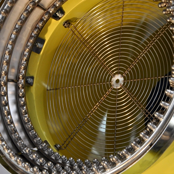 Eine gelbe Industriemaschine mit rundem Metallgitter und dichtem Drahtschutz zeigt eine technische Nahaufnahme von Ventilator und Gehäuse.